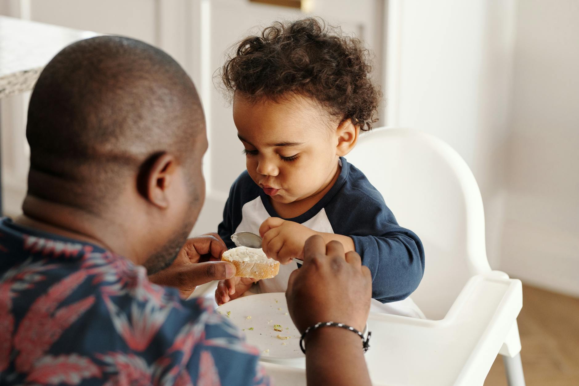 man feeding baby in feeding chair