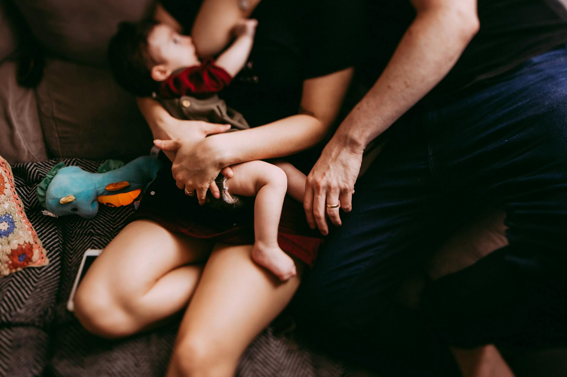 crop mother breastfeeding baby near father